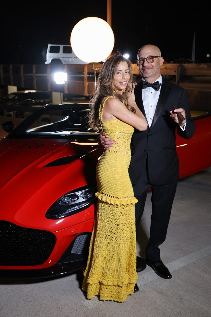 Couple standing with a red sports car at the event