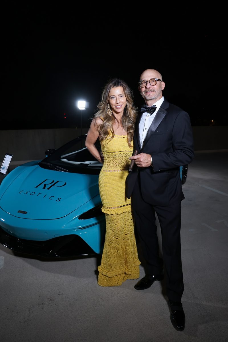 Couple beside a teal exotic car on the show floor
