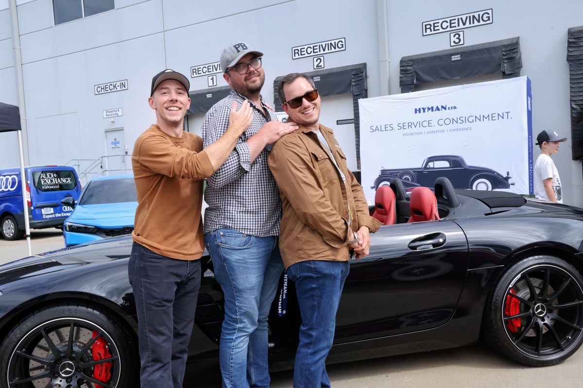 Guests beside a black convertible sports car
