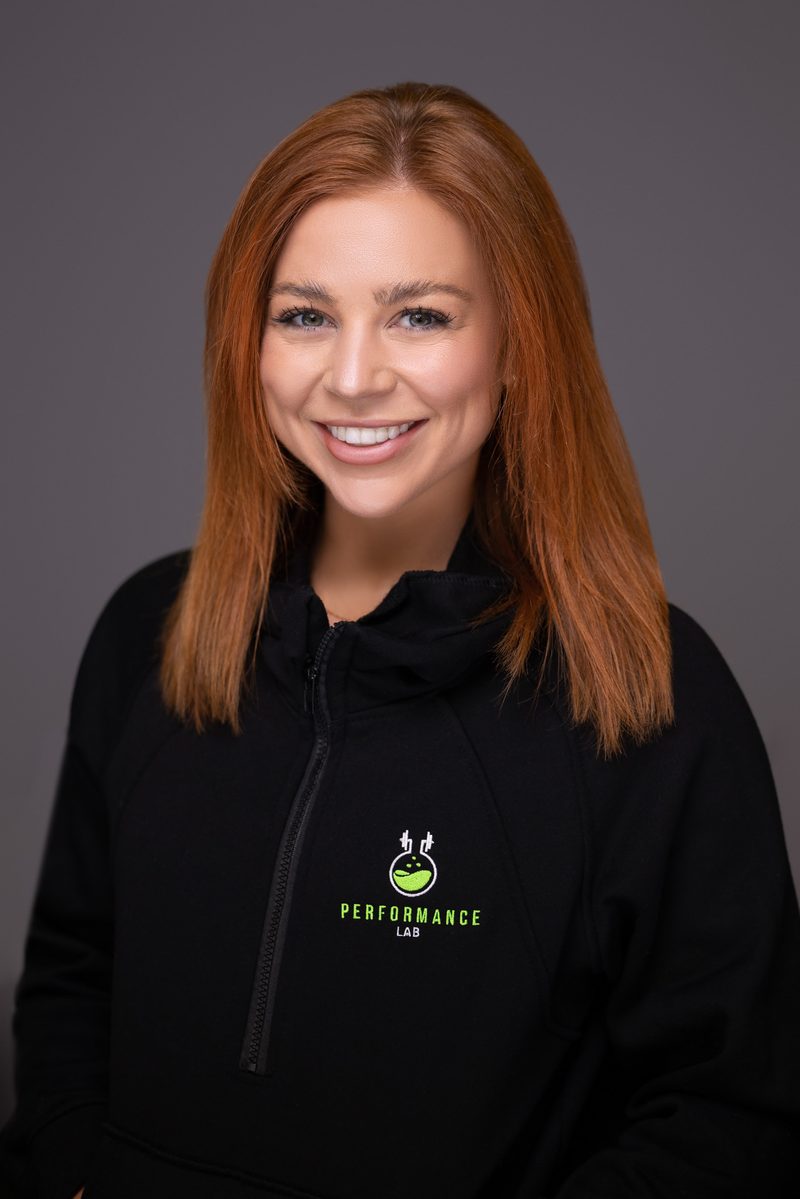 Studio headshot of a woman in a black polo on a dark background