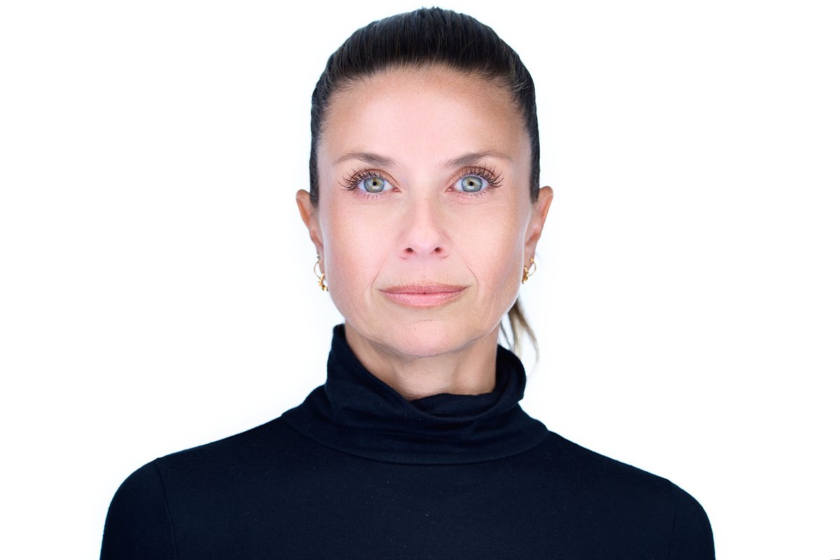 Studio headshot of a woman in a black turtleneck on a white background