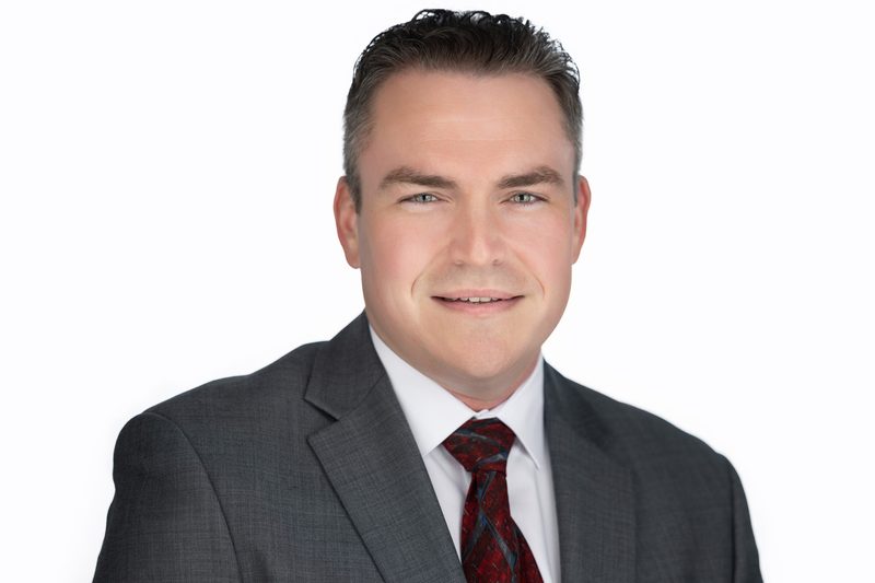 Corporate headshot of a businessman in a suit and tie on a white background