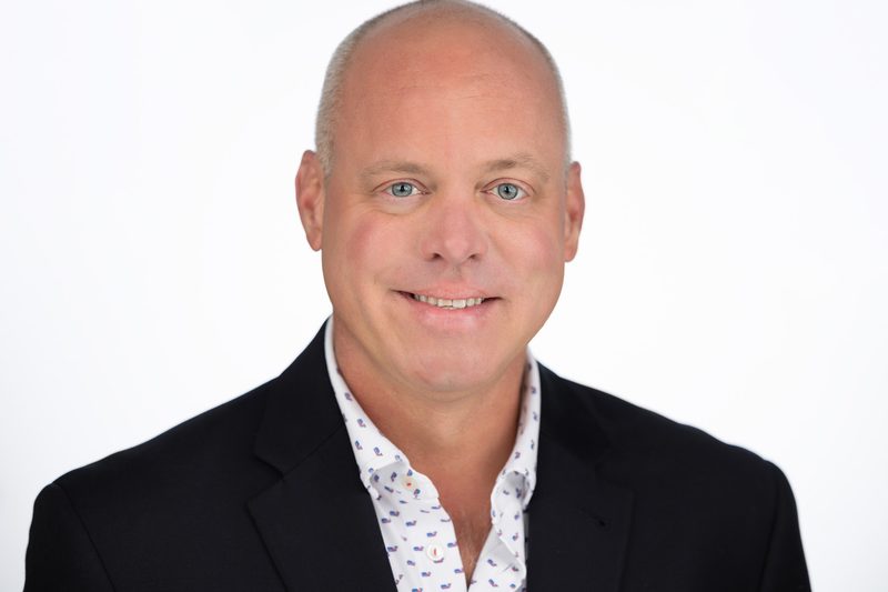 Corporate headshot of a businessman in a dark suit on a white background