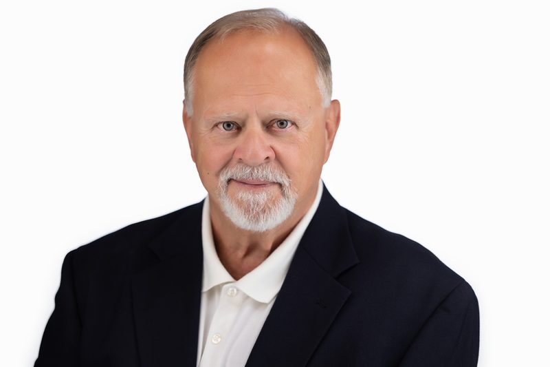 Corporate headshot of a bearded businessman on a dark background
