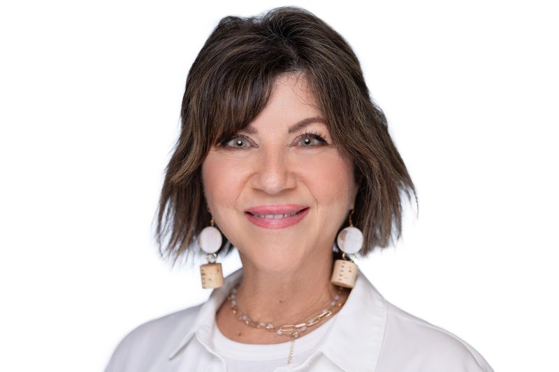 Studio headshot of a smiling brunette woman on a white background